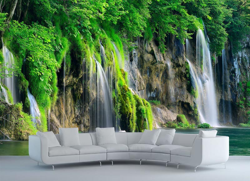 Bright waterfall cascading through green scenery into clear water