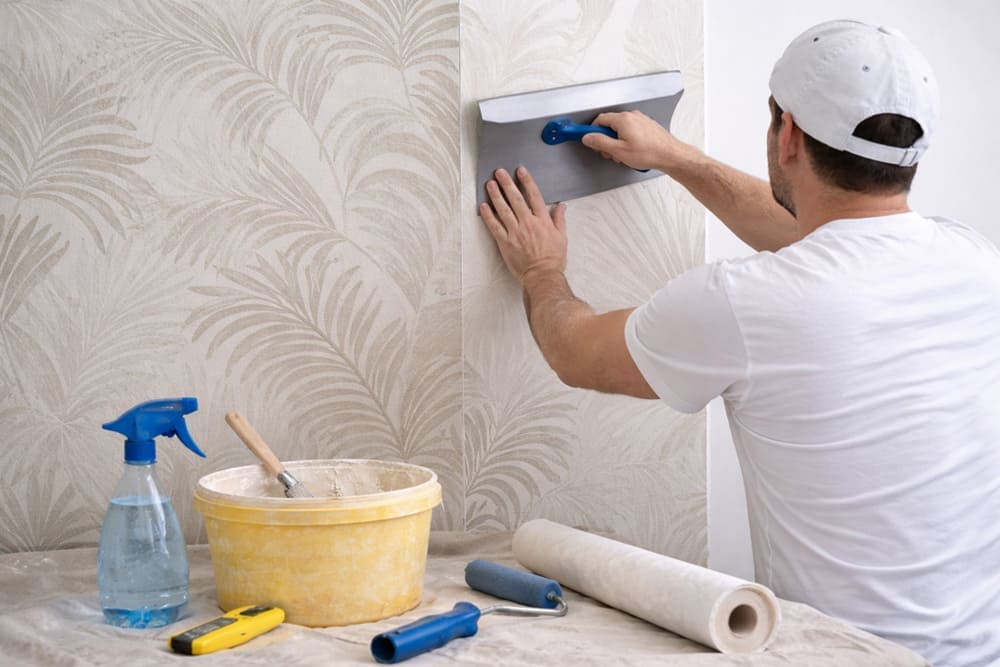 Step-by-step wallpaper installation using a wallpaper smoother on the wall